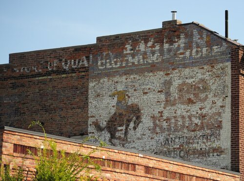 [Old Faded Advertising On Building in Downtown Area] style=